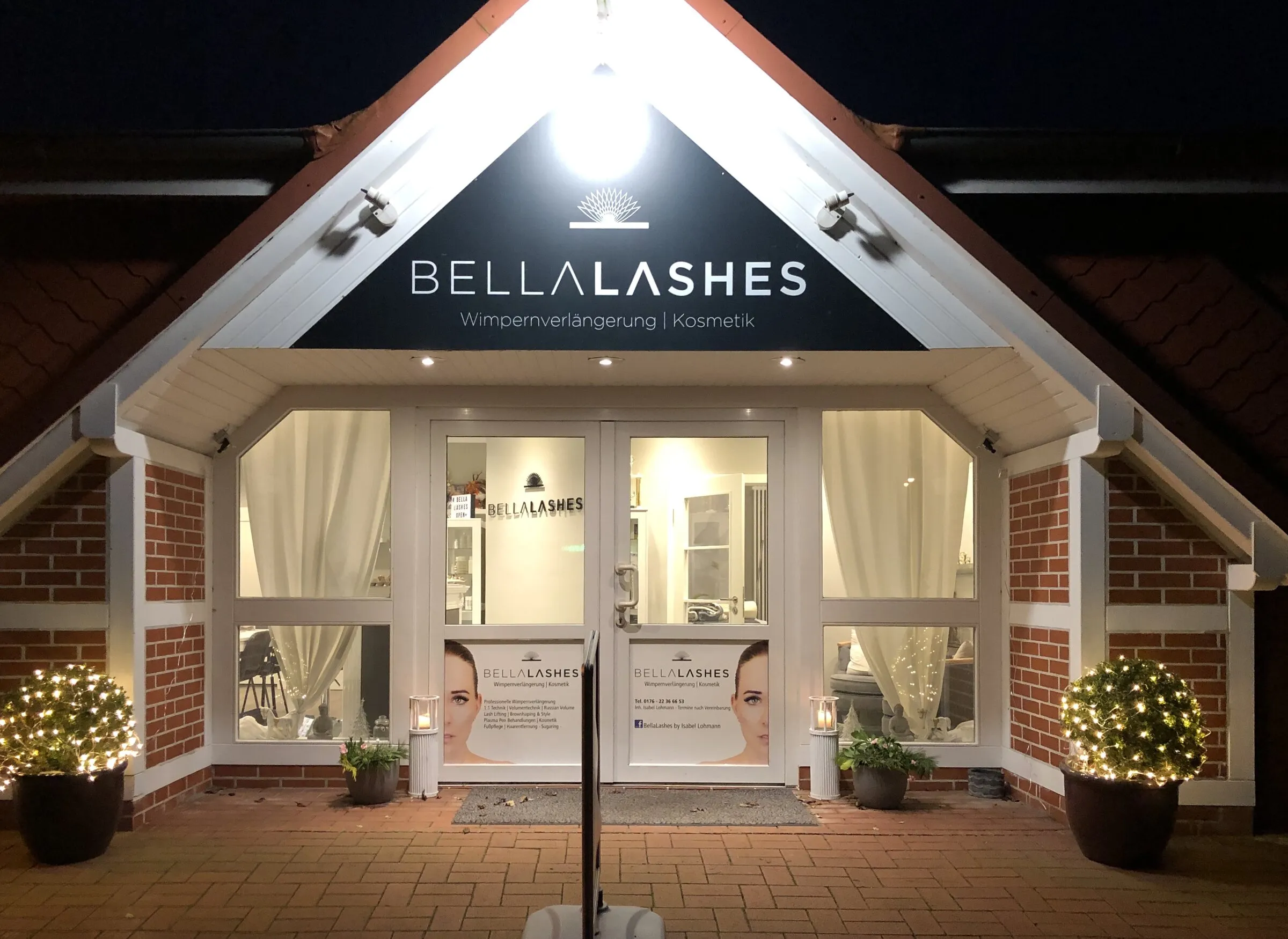 Das Studio Bellalashes von außen am Abend, beleuchteter Eingang mit Logo